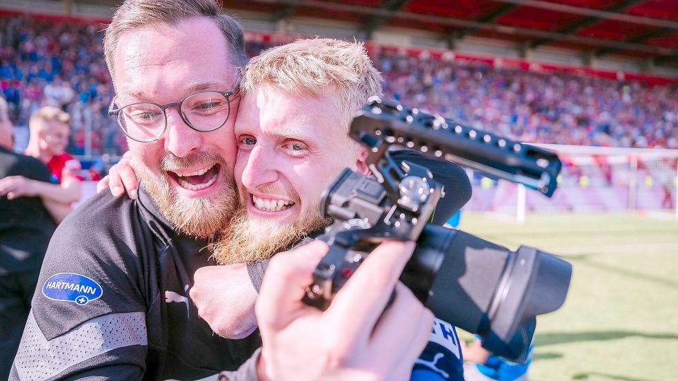 Den Heidenheimer Torschützen Jan-Niklas Beste im Arm, die Kamera in der rechten Hand: Tim Janssen jubelt nach dem Aufstieg in die Bundesliga. Fotos: Kevin Damrose/1. FC Heidenheim