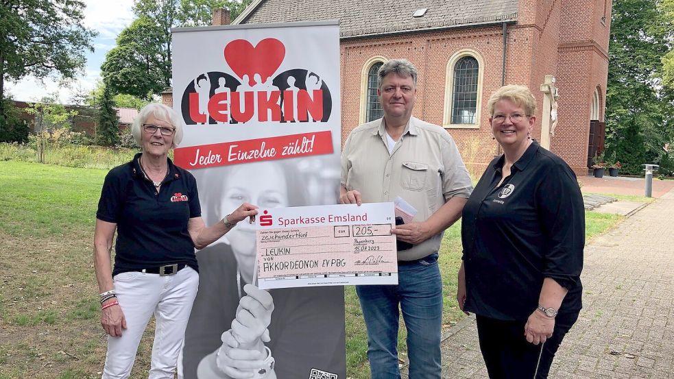 Christa Lindenberg (von links) freute sich über die Spende des Akkordeonorchesters Papenburg für die Registrierungsaktion. Ralf van der Pütten und Annette Lohe überreichten den symbolischen Scheck. Bei der Kirchengemeinde St. Bernhard Flachsmeer gingen für die Aktion mehr als 5000 Euro an Spenden ein. Zudem gab es Sachspenden wie Bratwurst, Kuchen und Getränke, die zum Kauf angeboten wurden. Foto Kruse