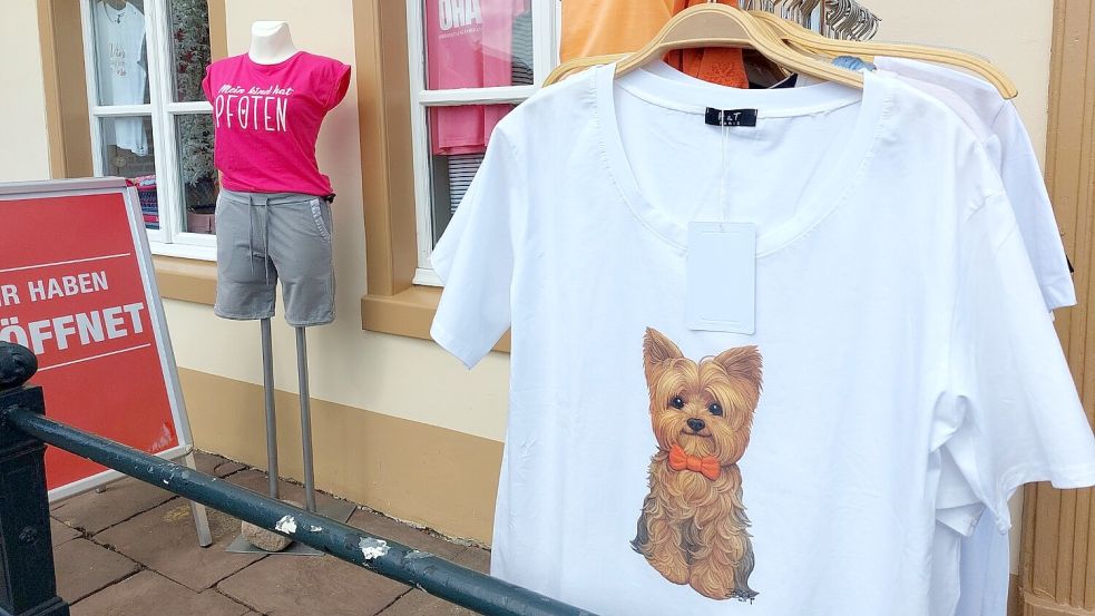 "Mein Kind hat Pfoten" steht auf dem T-Shirt links, das es in einer Boutique am Greetsieler Hafen zu kaufen gibt. Für viele Menschen ist der Hund ein vollwertiges Familienmitglied - und das kommt auch mit in den Urlaub. Foto: Hanssen