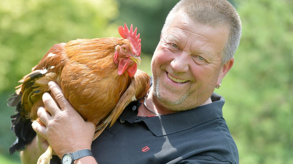 Dirk Heuermann aus Dietrichsfeld hat einen New Hampshire Hahn auf dem Arm. Die Tiere sind zwar nicht immer leicht zu bändigen, schmecken dafür aber gut, findet er. Foto: Ortgies