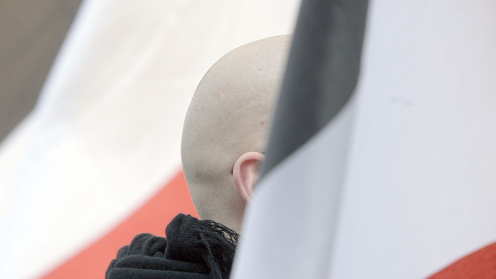 Ein Neonazi steht verdeckt auf einer Demonstration zwischen schwarz-weiß-roten Fahnen. Laut Polizei und Innenministerium gibt es in Ostfriesland keine rechtsextremen, organisierten Strukturen. Aber stimmt das? Symbolfoto: DPA
