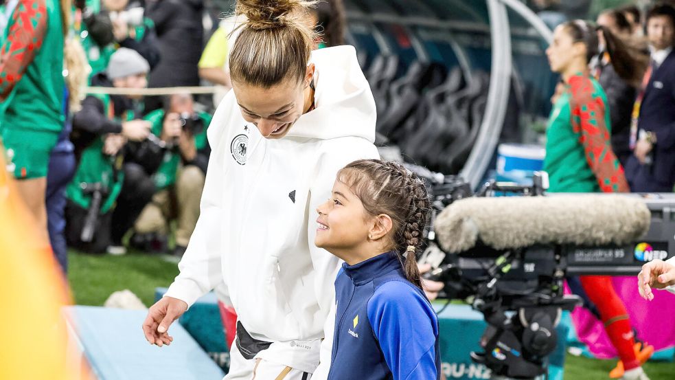 Felicitas Rauch aus dem DFB-Team betritt mit einem Einlaufmädchen den Platz. Für weibliche junge Fans sind Spielerinnen wie sie ein Vorbild. Foto: IMAGO images/Beautiful Sports