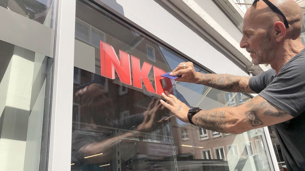 Der Werbetechniker Thomas Müller bringt das Firmenlogo von NKD an der Ladenfront an. Foto: H. Müller