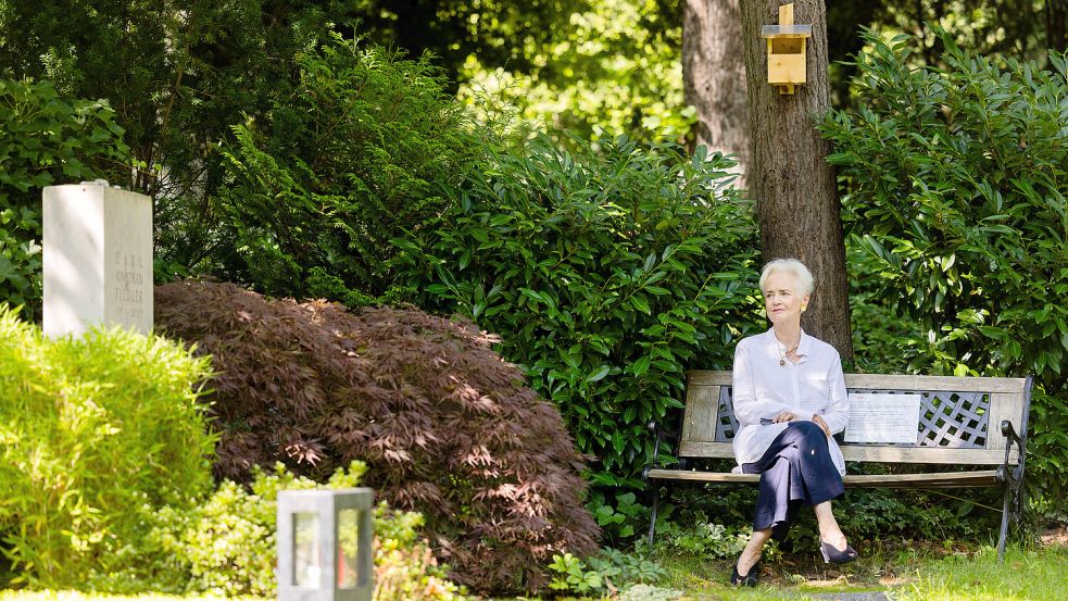 Dorothee Fiedler, Initiatorin einer Petition zum Erhalt der privaten Bänke auf dem Melaten-Friedhof, sitzt auf einer Bank am Grab ihres Sohnes. Foto: Vennenbernd/dpa