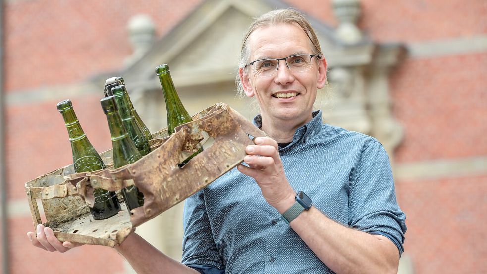 30 Flaschen passten in die alten Bierkästen aus Metall, von denen Dr. Jan Kegler ein Exemplar der „Ostfriesischen Actien-Brauerei Aurich“ präsentiert. Mit den schweren Flaschen wogen sie samt Inhalt mindestens 25 Kilogramm. Dieser Kasten war an einem Pflug hängengeblieben und wurde so entdeckt. Foto: Ortgies