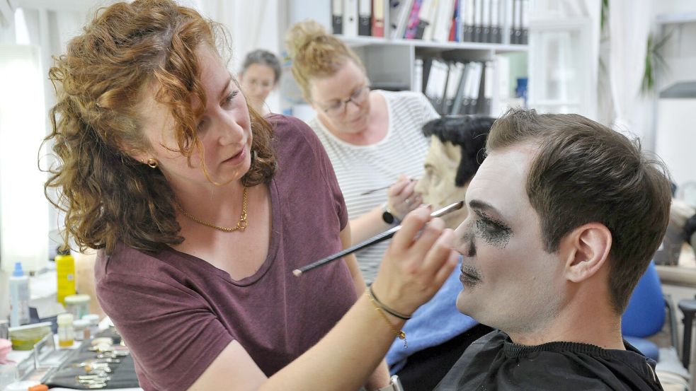 Maskenbildnerin Lisa Metzner schminkt ein Ahnen (Kevin Focke) mit gekonnten Pinselstrichen und den passenden Farbtönen ein paar Jahrhunderte älter. Im Hintergrund legt Eva Brodowski Hand an den Butler Lurch (Sven Heiß). Foto: Ullrich