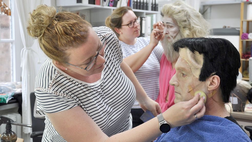 Maskenbildnerin Eva Brodowski verhilft Buttler Lurch (Sven Heiß) zu Leichenblässe. Im Hintergrund bekommt Grandma Addams (Sibylle Hellmann) von Sonja Gast den letzten Schliff. Foto: Ullrich