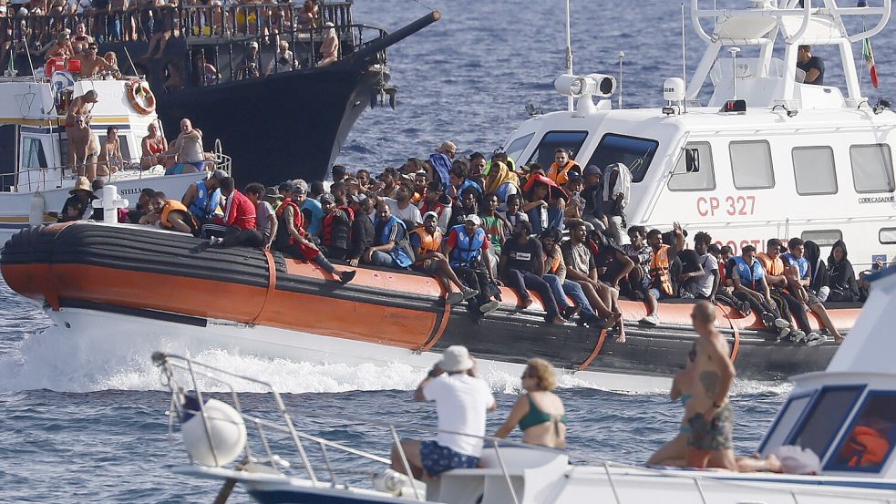Die italienische Küstenwache transportiert Geflüchtete unter den Augen von Touristen nach Lampedusa. Foto: dpa/LaPresse/AP | Cecilia Fabiano