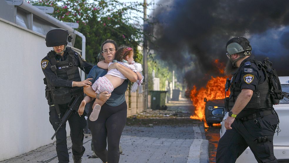 Polizisten schützen eine Frau und ihr Kind, nachdem eine Rakete aus dem Gazastreifen Aschkelon im Süden Israels getroffen hat. Foto: AP Photo/Tsafrir Abayov, File
