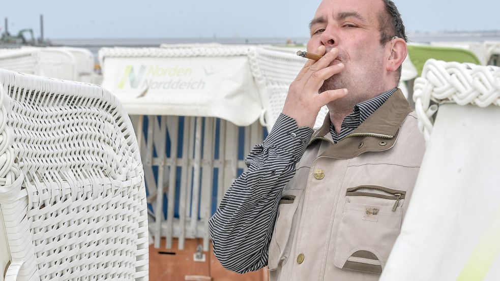 Ein Mann genießt am Strand von Norddeich entspannt seinen Zigarillo. Auf Borkum sollen die Überreste demnächst gesammelt werden. Foto: Archiv/Ortgies