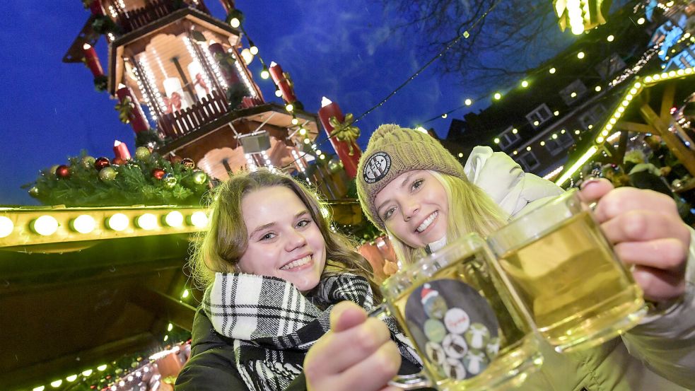 Sina Büscher (links) und Josephine Bakker stoßen am Montagnachmittag schon einmal auf dem Emder Weihnachtsmarkt an. Foto: Ortgies