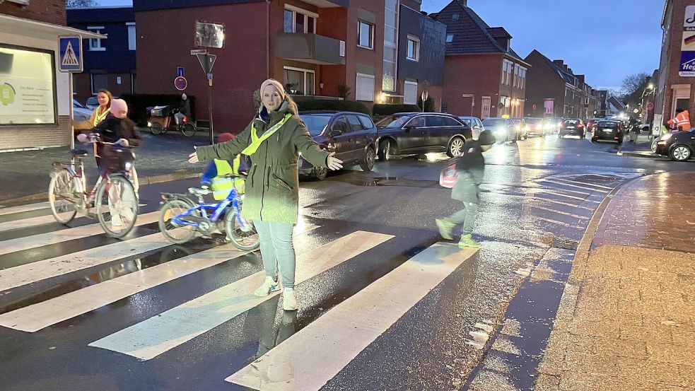 Stopp: Grietje Küper und Darinka Herrmann geleiten Schülern mit ausgebreiteten Armen über den Zebrastreifen. Für den Auto-Rückstau ist die Ampelkreuzung verantwortlich. Foto: Schuurman