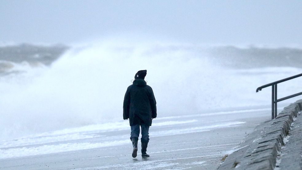 Eine Spaziergängerin läuft bei stürmischem Wetter am Nordstrand der ostfriesischen Insel Norderney. Foto: Bartels/DPA/Archiv