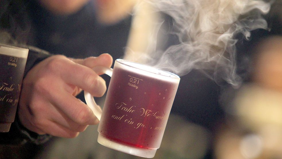 Auf dem Weihnachtsmarkt wird eine Tasse mit Glühwein gehalten. Foto: Karl-Josef Hildenbrand/dpa