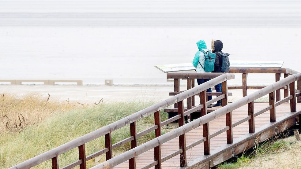Zwei Frauen stehen bei regnerischem Wetter auf einer Aussichtsplattform in Norddeich und schauen auf die Nordsee. Foto: Dittrich/dpa