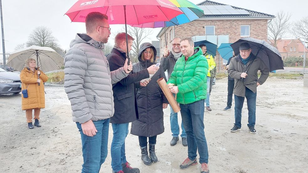 Traditionell wurde bei der Grundsteinlegung der Senioren-Wohnanlage in Petkum eine sogenannte Zeitkapsel eingemauert. Monika (Mitte) und Arkadius Krey (rechts neben ihr mit Schirm) und GMP-Projektleiter Henning Zwafink (links neben ihr) füllten die Kapsel mit einer Tageszeitung, Cent-Stücken und anderem. Foto: Hanssen