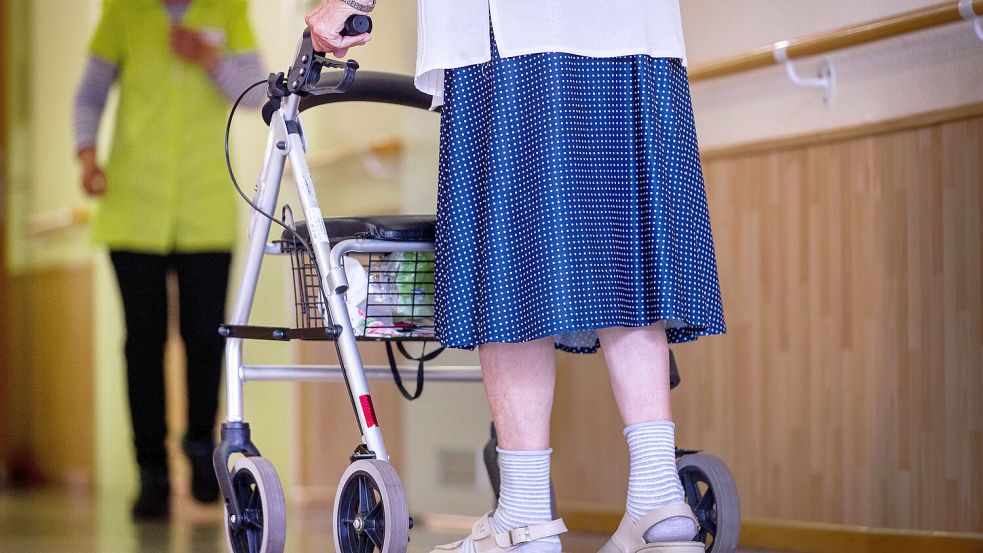 Eine Bewohnerin eines Pflegeheims geht mit ihrem Rollator über einen Flur. In Emden schließt ein Seniorenzentrum überraschend, was einen Umzug der Bewohnerinnen und Bewohner notwendig macht. Symbolfoto: Jens Büttner/dpa