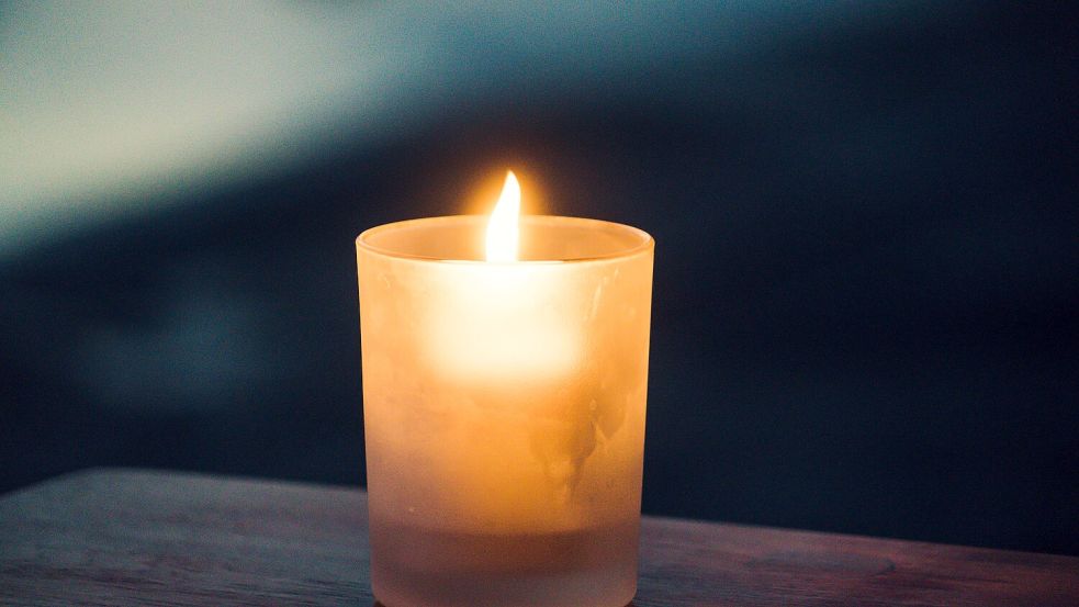 Eine Kerze brennt in einem Glas. Ein Zeichen des Gedenkens. Foto: Unsplash/Paolo Nicolello