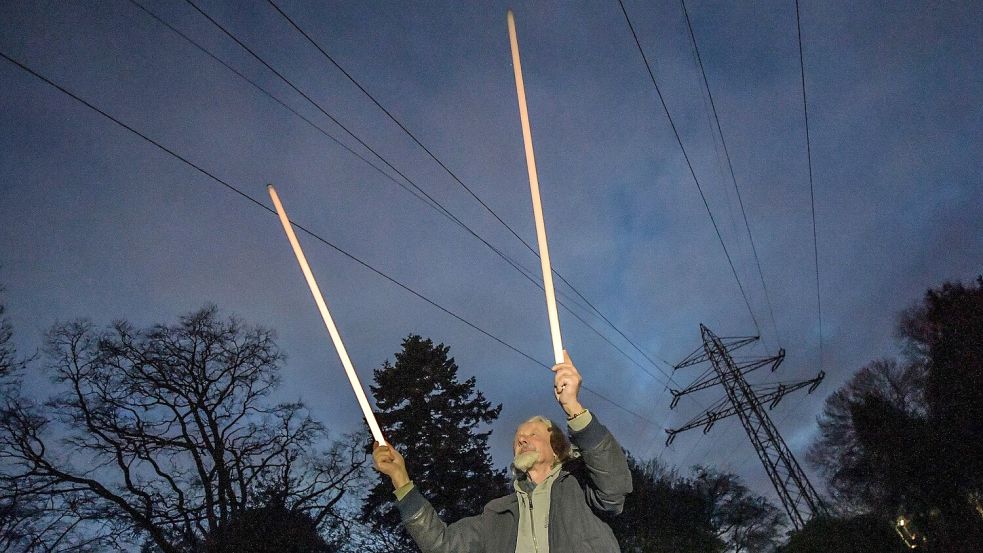 Edgar Weiss bringt Licht ins Dunkel. Die Leuchtstoffröhren werden allein durch die elektrische Ladung der Luft im Bereich unter den Leitungen zum Leuchten gebracht. Foto: Ortgies