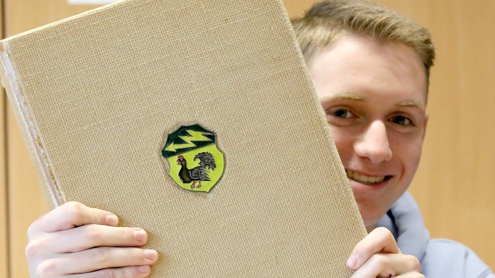 Der Auszubildende Tim Pollmann mit einer der Chroniken des Lehrers Ernst Amelong über die Wiesmoorer Geschichte. Foto: Böning