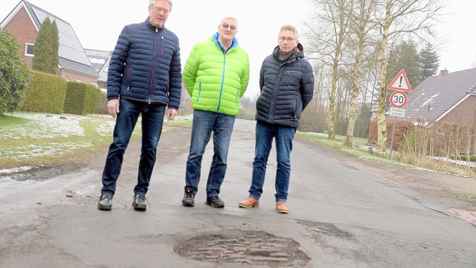 Bereits Anfang Januar hatten die Anwohner Friedemann Kretzer (von links), Menhard Brümmer und Erich Buss auf die vielen Löcher in der Rorichmoorer Straße aufmerksam gemacht. Bisher kann die Gemeinde Moormerland die Krater nicht dauerhaft reparieren. Foto: Lüppen