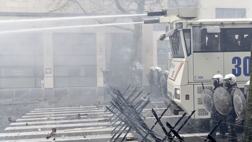 Mit Wasserwerfern, Helm und Schild versucht die Polizei, die eskalierte Situation unter Kontrolle zu bekommen. Foto: dpa/Harry Nakos