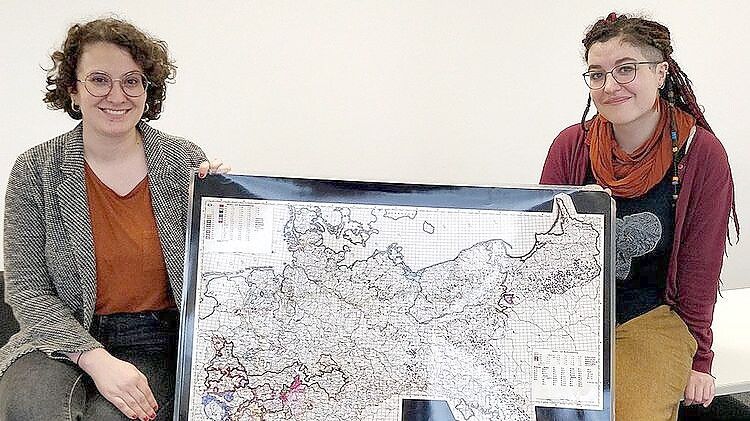 Marina Frank (links) und Marina Rohloff von der Universität Oldenburg zeigen eine Karte, die Lokaldialekte zeigt. Die beiden Forscherinnen haben das Plattdeutsche in der Krummhörn untersucht. Foto: Universität Oldenburg