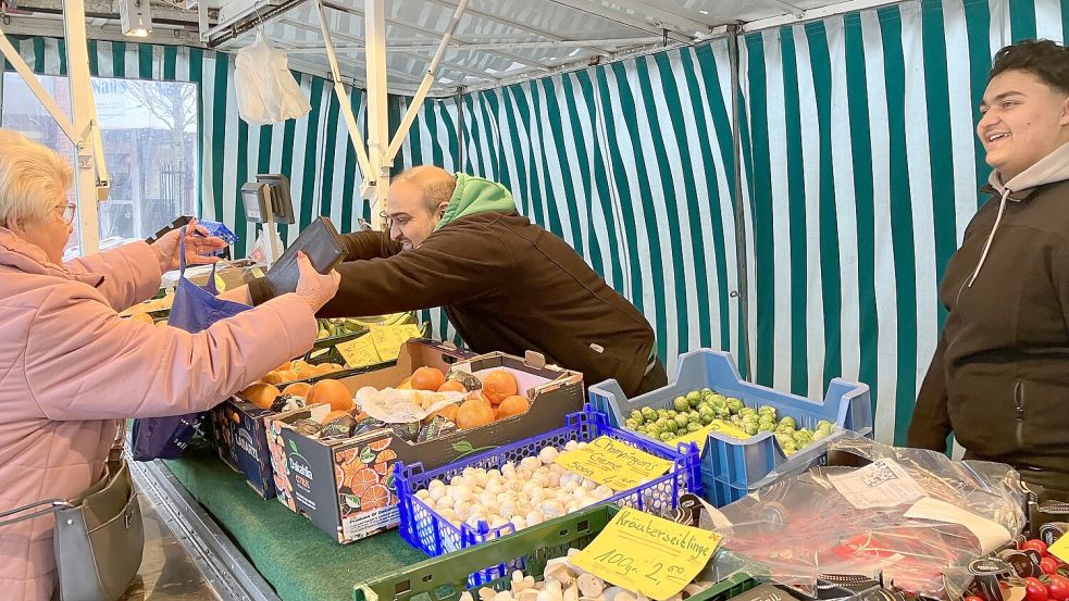 Finden den Emder Wochenmarkt „lohnenswert“: Musli und Harbin Tafa aus Weener - hier mit einer Stammkundin. Foto: Schuurman