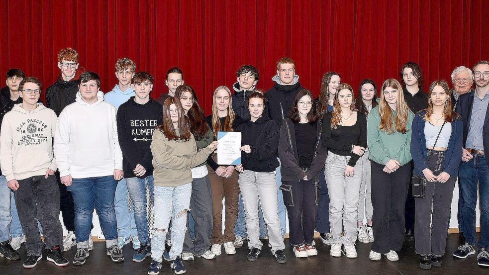 IGS-Koordinator Hannes Ohlhoff (von rechts), Moormerlands Bürgermeister Hendrik Schulz und Folkert Laupichler vom Volksbund Deutsche Kriegsgräberfürsorge freuten sich mit der Schülerschaft über das beeindruckende Sammelergebnis. Foto: Stromann