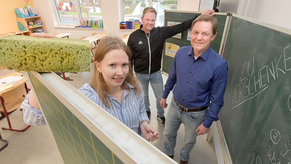 Ralf Möhlmann von der Samtgemeinde Jümme (von rechts), Gunnar Hein, Schulleiter in Filsum, und Elske Schulte aus der Kämmerei der Samtgemeinde präsentieren eine der zu verschenkenden Tafeln. Foto: Ortgies