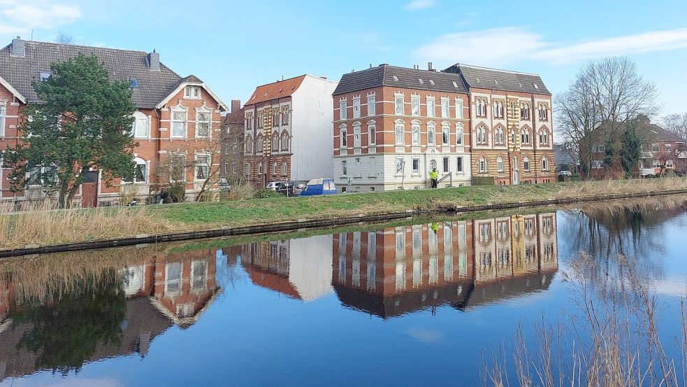 Ein Anblick, den es nach dem Sommer wohl nicht mehr geben wird: Die drei Häuser an der Ligariusstraße (rechts) spiegeln sich im Wasser des Ems-Jade-Kanals. Sie sollen abgerissen werden. Foto: Hanssen