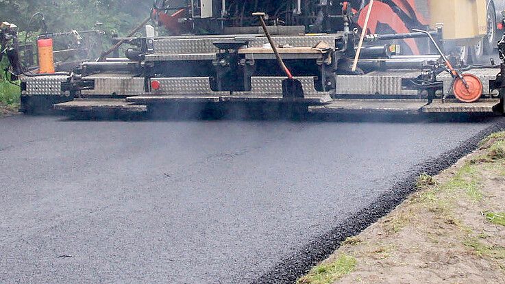 Asphalt wird im August 2015 auf die Kreisstraße 111 aufgetragen. Foto: Romuald Banik