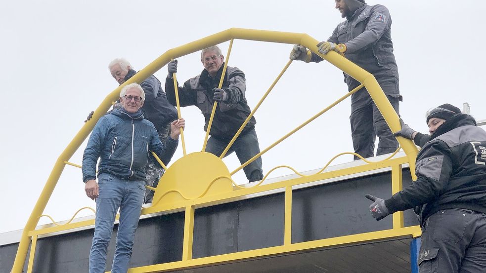 Technikchef Friedhelm Jakobs (vorne links), die Helfer Johann Olthoff (oben links), Alt-Technikchef Peter Kurzak (3. von links) und Mitarbeiter der Schlosserei Jakobs montierten die Sonnen-Konstruktion über dem Eingang des Van-Ameren-Bades. Foto: H. Müller