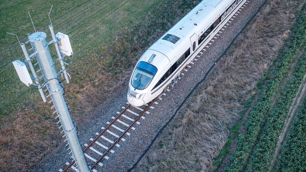 Ein Testzug der Deutschen Bahn fährt an einer der Antennenmasten für das 5G-Bahnprojekt vorbei. Foto: Jens Büttner/dpa