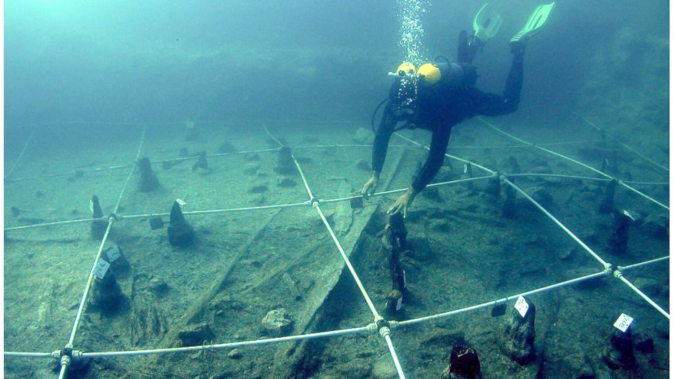 Ein Kanu wird Boden des Braccianosees ausgegraben. Die abgenutzten Überreste der mehr als 7000 Jahre alten Kanus lassen erahnen, wie ausgeprägt das Wissen über die Seefahrt bereits in der Jungsteinzeit war. Foto: Gibaja Et Al/2024, Plos One, C/dpa