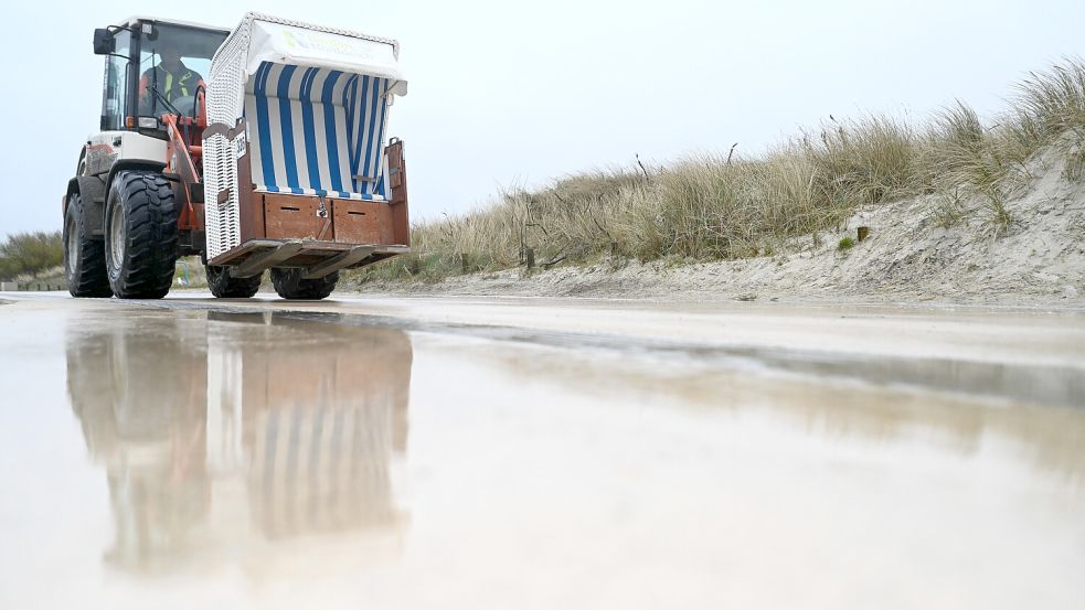 Christian Striek bringt die Strandkörbe mit einem Radlader an den Strand. Foto: Lars Penning/dpa