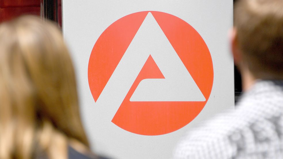 Zwei Personen stehen vor dem Logo der Agentur für Arbeit. Foto: Rehder/DPA