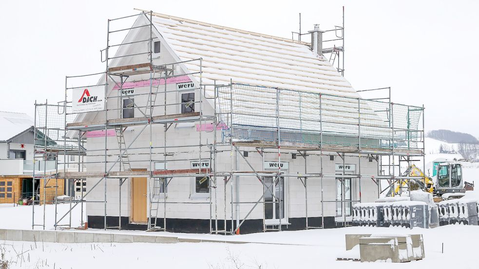 Der Rohbau eines Einfamilienhauses in einem verschneiten Baugebiet. Das Bild entstand in Sachsen. Foto: Woitas/dpa
