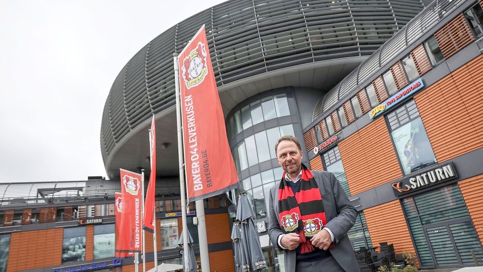 Uwe Richrath, Oberbürgermeister von Leverkusen, steht mit einem Fanschal vor dem Rathaus. Foto: Oliver Berg/dpa