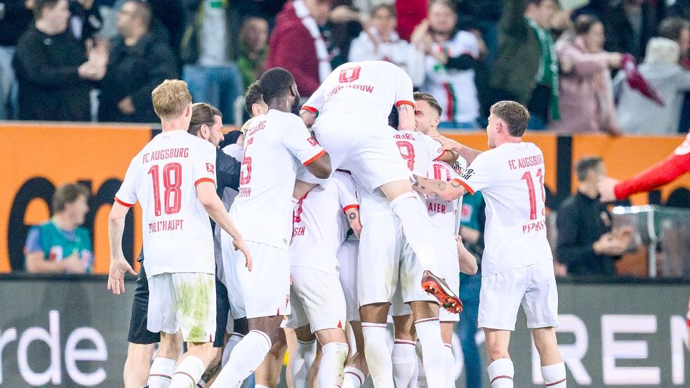 Die Augsburger Spieler feiern den Sieg gegen den 1. FC Union Berlin. Foto: Tom Weller/dpa