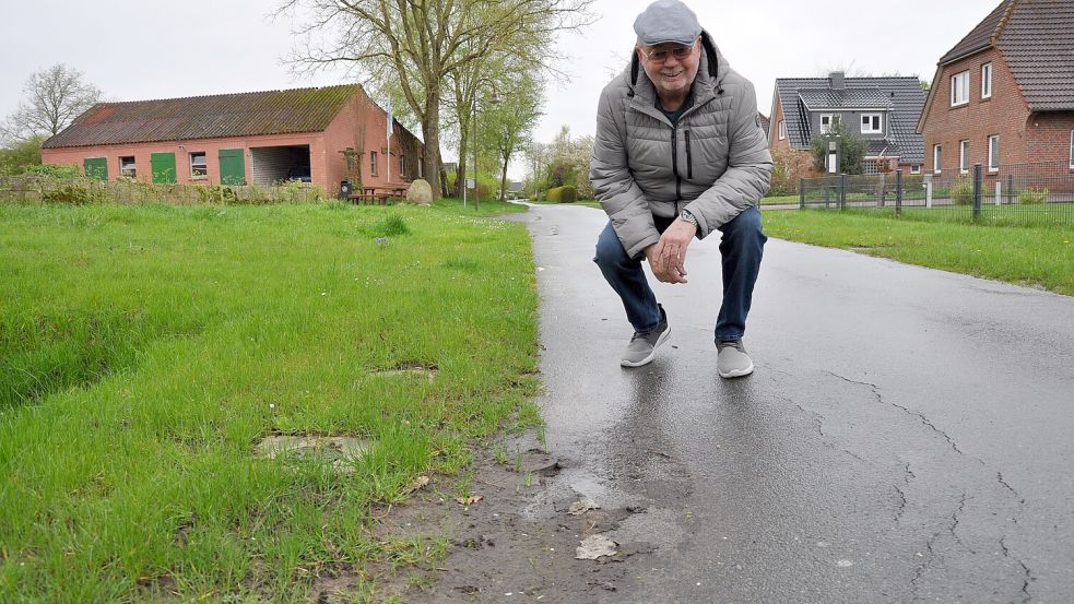 Anfried Arends an der Einmündung des Kattrepelwegs zu einem Grundstück. Er sieht in den Rissen in der Fahrbahn und dem abgesackten Bereich hin zum Grünstreifen deutlich sichtbare Folgen von Tiefbauarbeiten. Foto: Ullrich