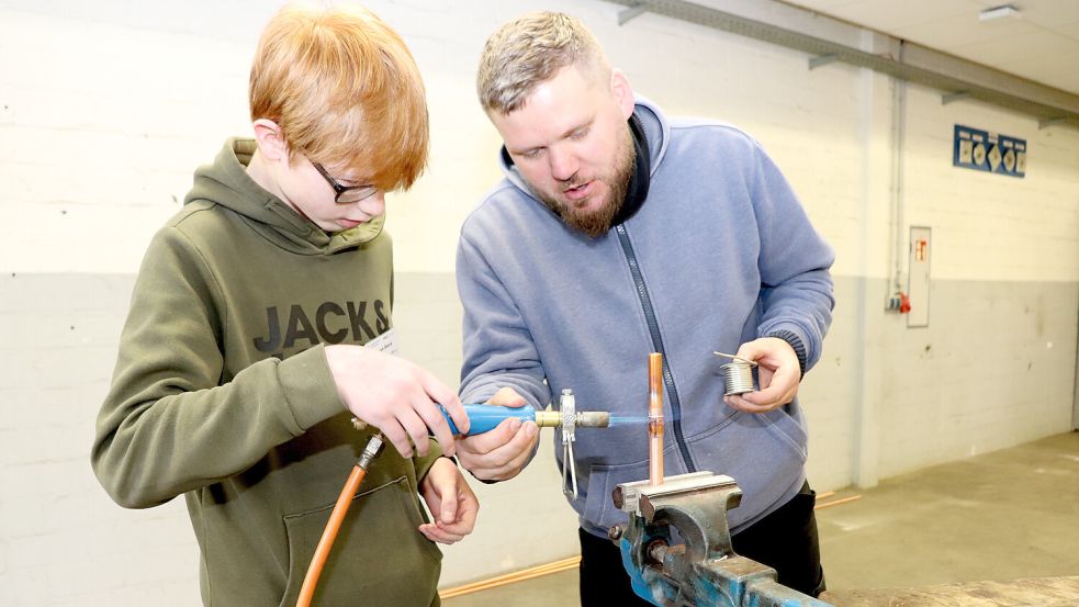 Lehrwerksmeister Aike Schierenberg zeigt Jonah Block (14) aus Blomberg, wie er mit dem Propan-Brenner arbeiten muss. Foto: Handwerkskammer/Feldmann