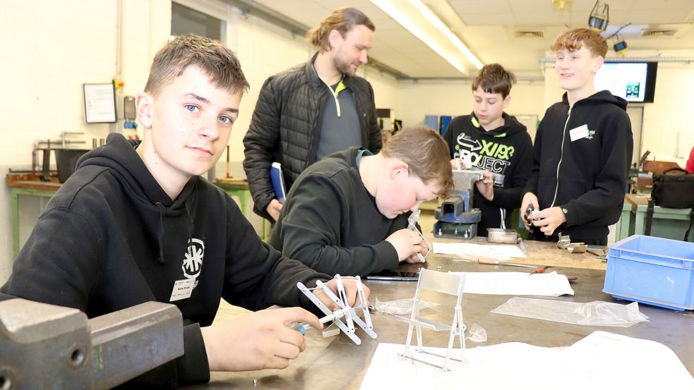 In der Metallwerkstatt konnten Jugendlichen von der Friederikenschule Großheide ihr handwerkliches Talent erproben. Sie bauten einen Miniklappstuhl aus Metall. Malte Strube (14 Jahre, vorne) aus Großheide möchte später Feinwerkmechaniker werden. Mit dabei waren (von links) Tilko Diekmann aus Berumbur, Connor Gatena aus Hage und Sören Alberts aus Münkeboe. Klassenlehrer Alexander Wadehn schaut den Jungen bei der Arbeit über die Schulter. Foto: Handwerkskammer/Feldmann