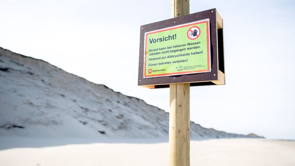 Ein Schild mit der Aufschrift „Vorsicht!“ steht vor der Abbruchkante am Nordstrand der Insel Norderney. Die Aufnahme entstand im März 2022. Foto: Dittrich/dpa