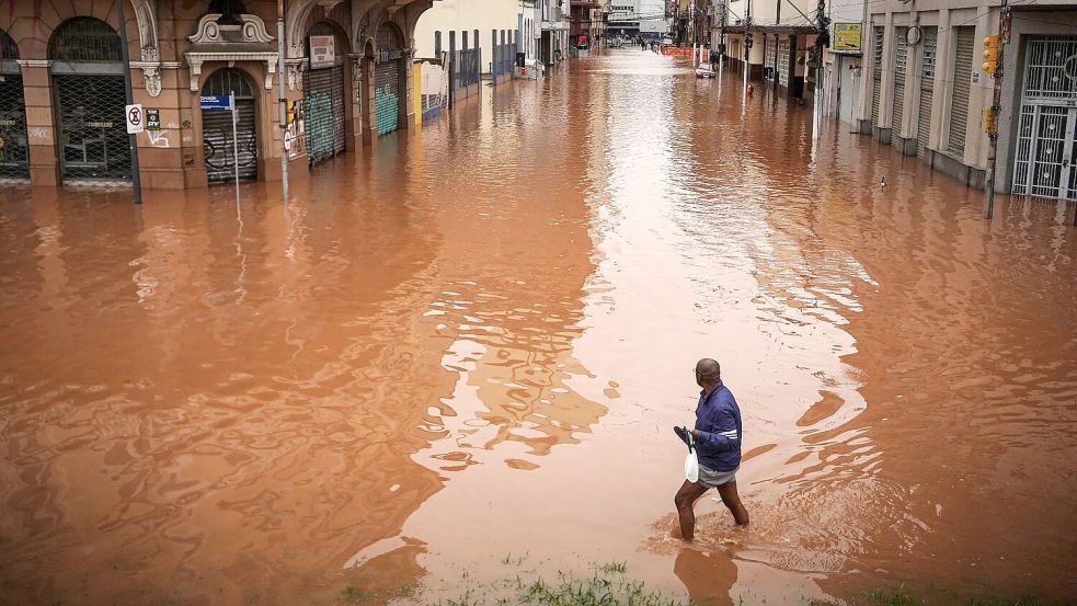 Ein Mann watet in Porto Alegre im brasilianischen Bundesstaat Rio Grande do Sul durch ein von schweren Regenfällen überschwemmtes Gebiet. Foto: Carlos Macedo/AP/dpa