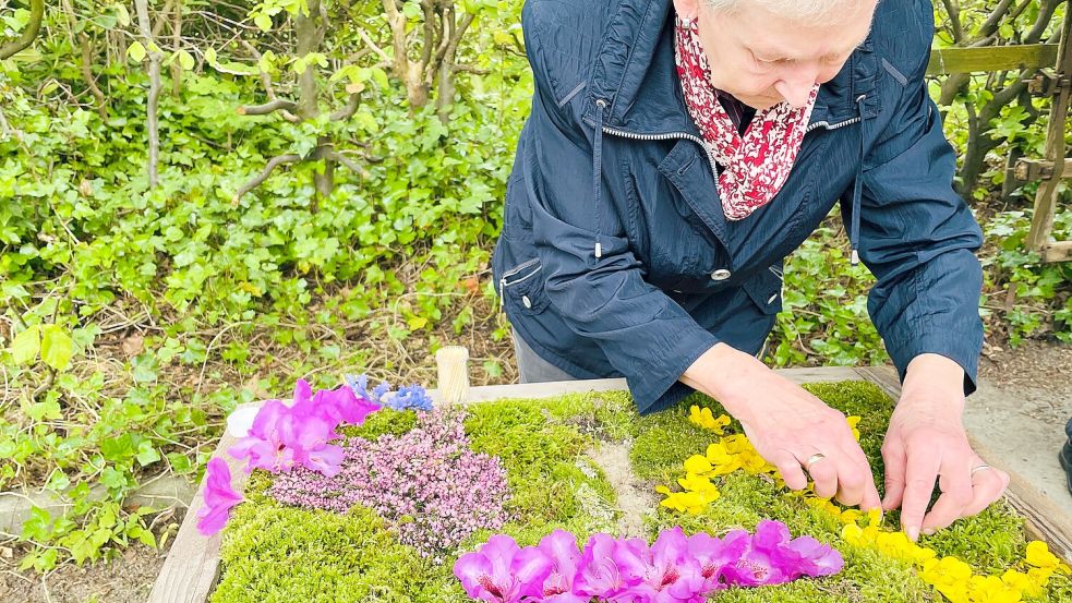 Mit einem Zahnstocher bohrt Anneliese Schoon zunächst ein Loch in den weichen Untergrund, in das sie dann den Blütenstängel steckt. Foto: Buß