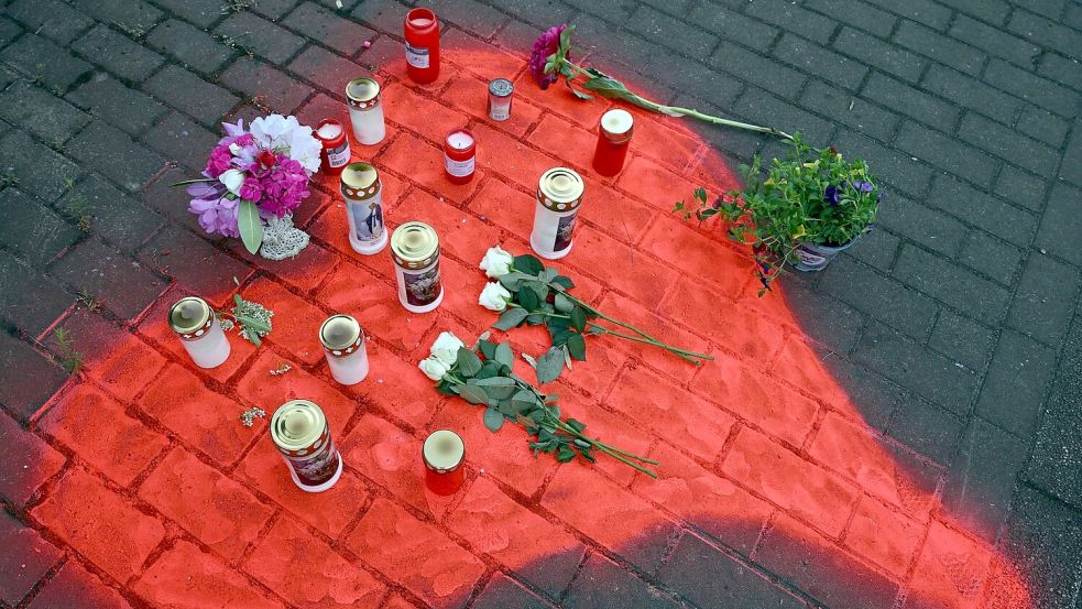 Kerzen und Blumen liegen in einem auf das Pflaster gesprühten roten Herzen in Düsseldorf nach dem mörderischen Brandanschlag. Foto: Federico Gambarini/dpa