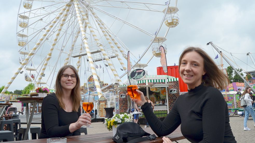 Mit Aperol Spritz stießen Kim Dziubale (links) und Julia Fennen vor der Kulisse des Riesenrades auf dem Fehntjer Markt an. Foto: Fertig