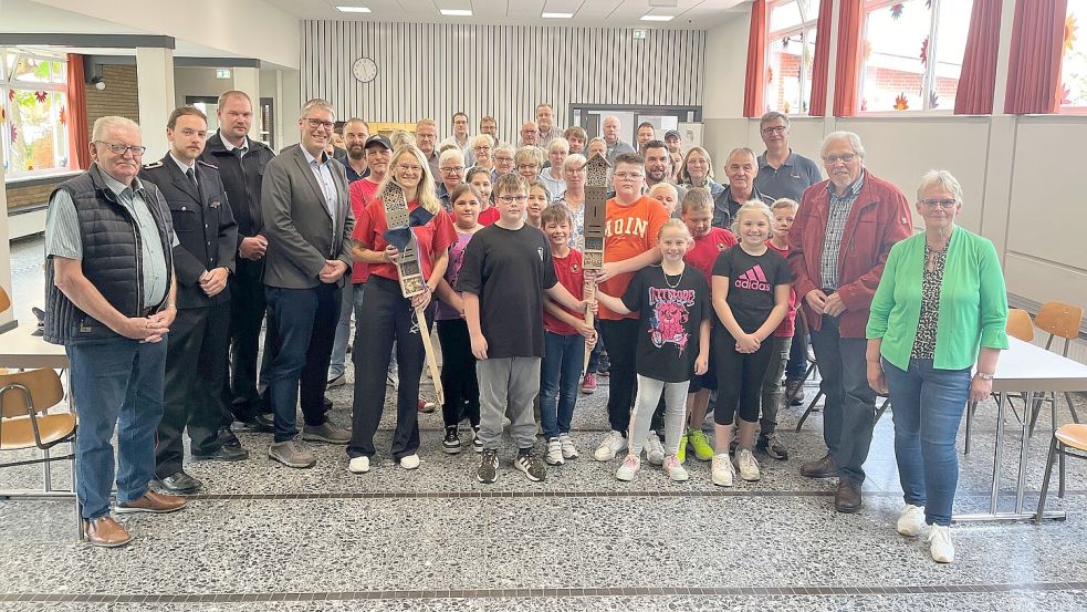 Gruppenbild mit Gästen: Bei der Eröffnung der umgebauten Schulaula überreichte Bürgermeister Heiko Abbas Schulleiterin Gabi Gödecke (vordere Reihe, 4. und 5. von links) und Schülern der Klasse 4 b zwei Insektenhotels, die draußen vor dem Gebäude ihren Platz finden sollen. Foto: privat