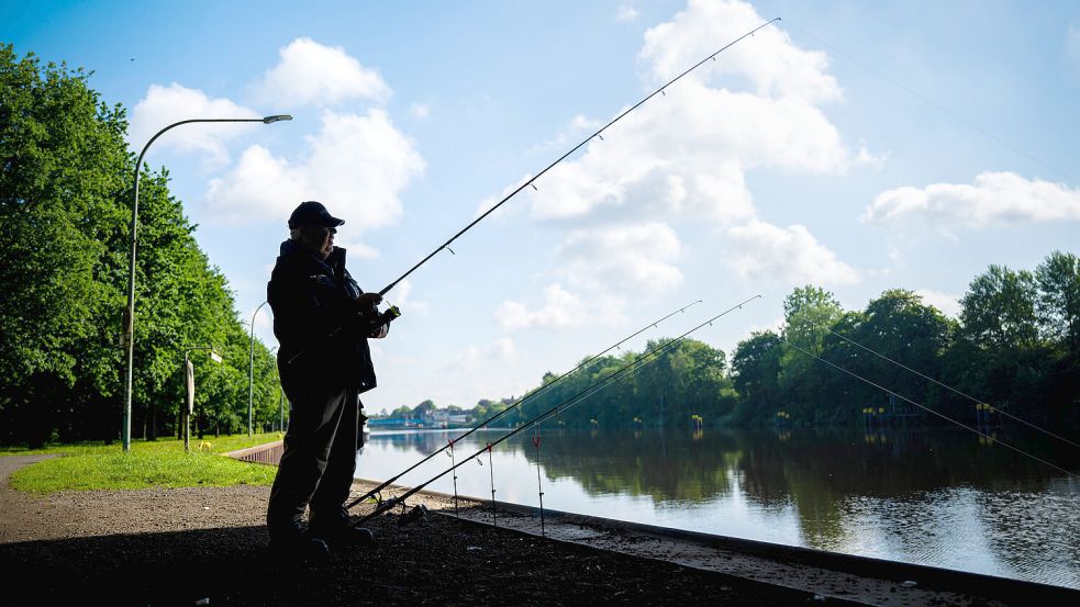 Ein Angler steht am Ufer der Hunte. Das Wetter in Niedersachsen taugt derzeit noch wenig zum T-Shirt-Tragen. Foto: dpa/Sina Schuldt